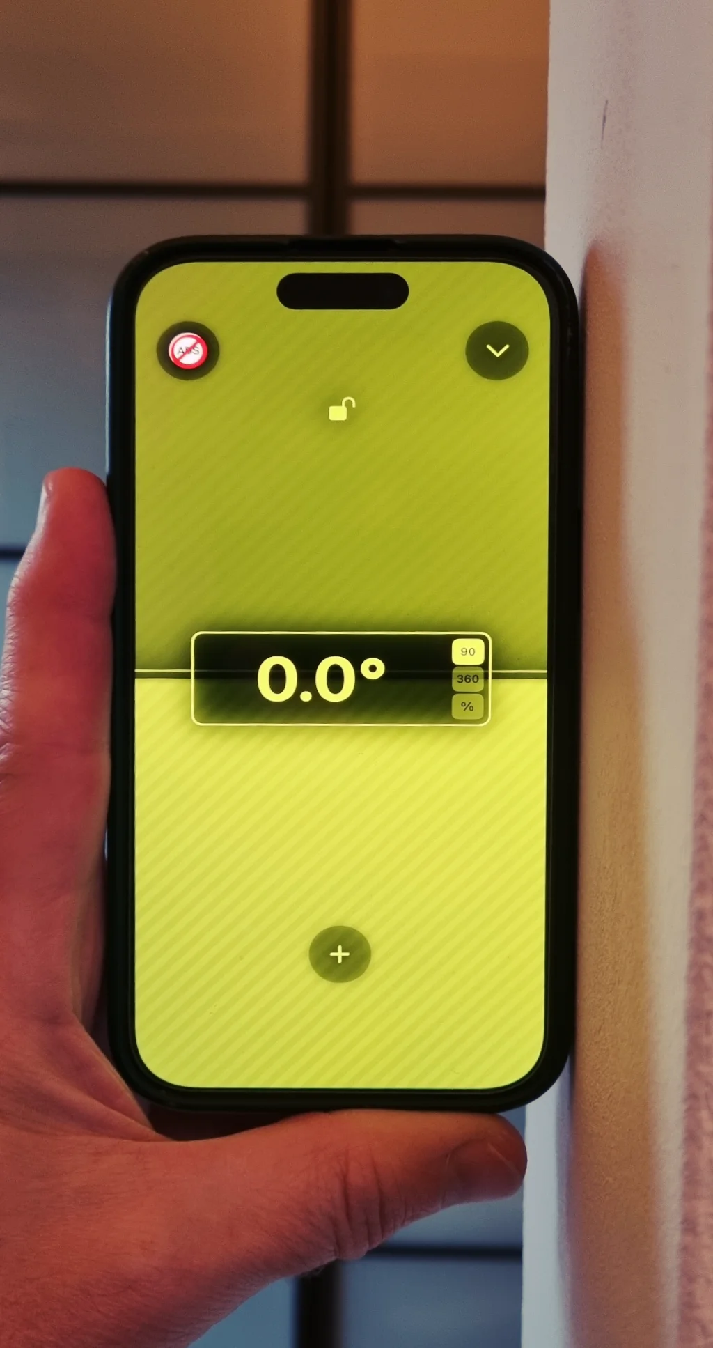 Smartphone held against a wall showing 0.0° in vertical inclinometer mode